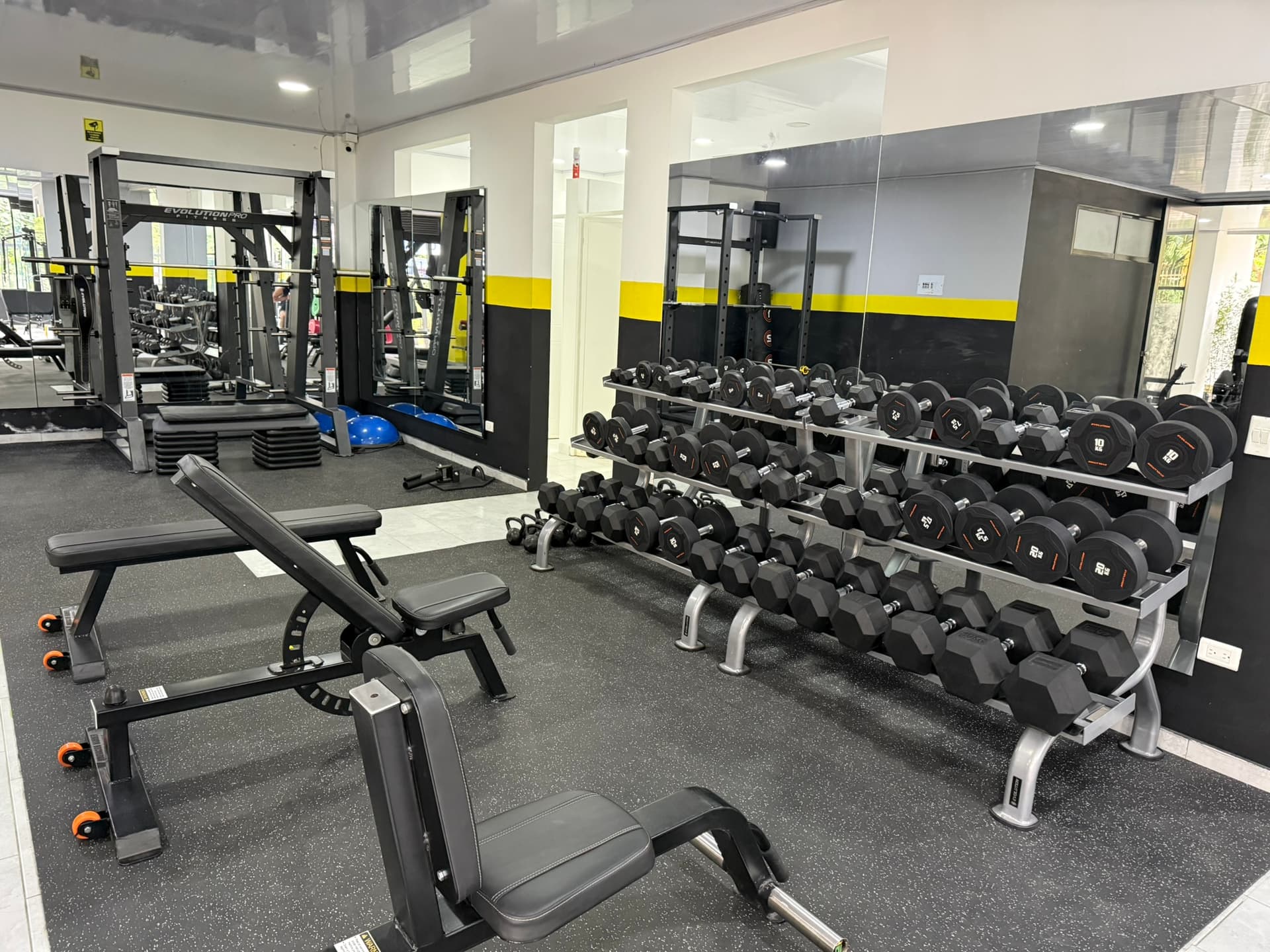 Interior de ATHOS Gimnasio: zona de peso libre con mancuernas y máquina Smith